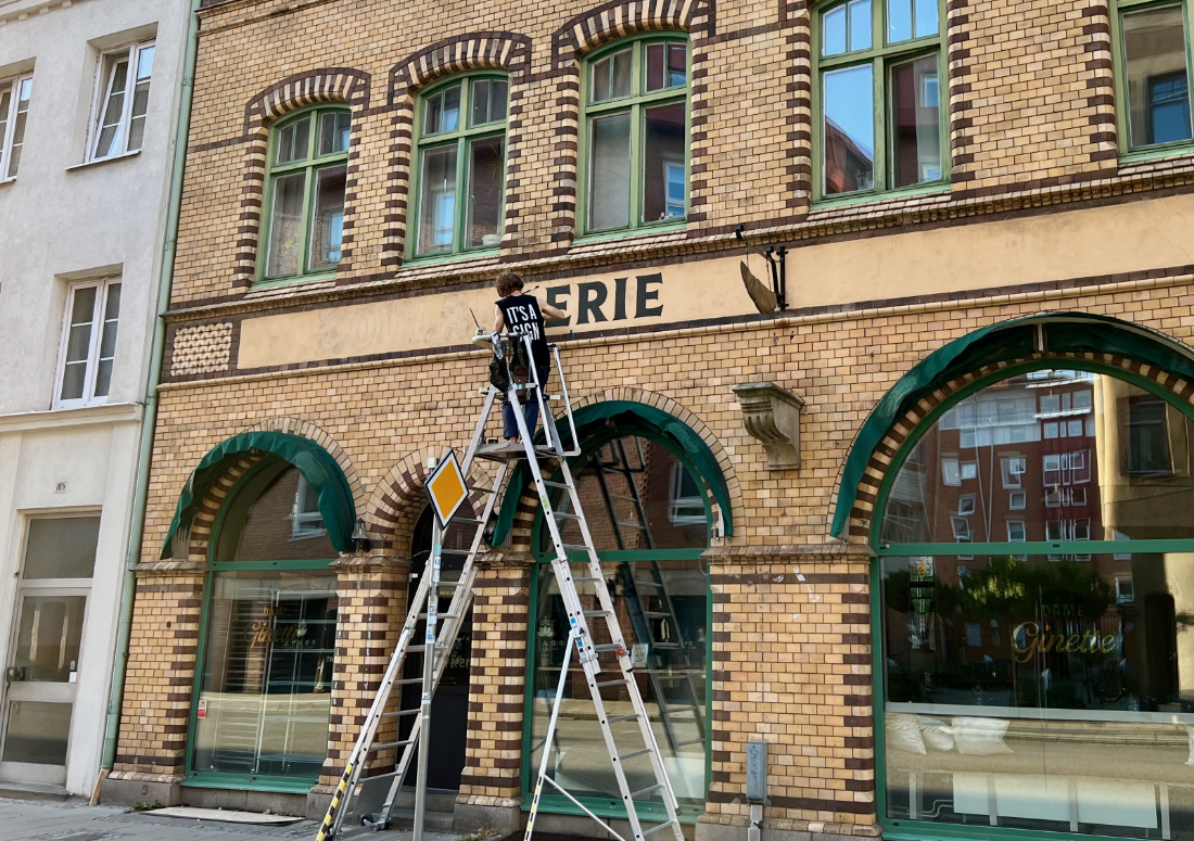 A women writing on the wall above a shop.